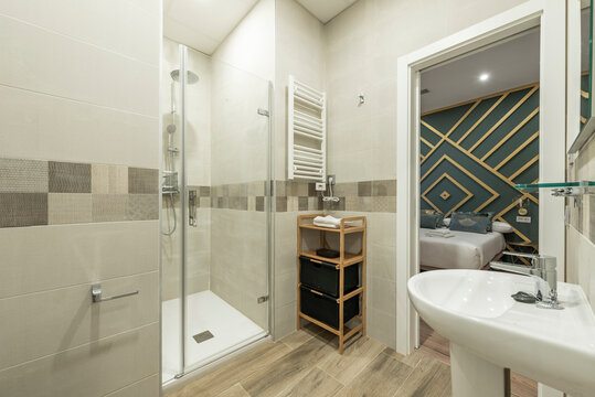 Bathroom with shower cabin with glass door, wooden furniture and white porcelain sink