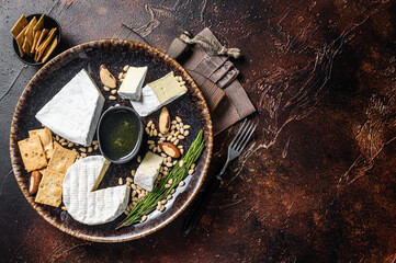 Cheese plate with brie and camembert on rustic plate with nuts and honey. Dark background. Top view. Copy space