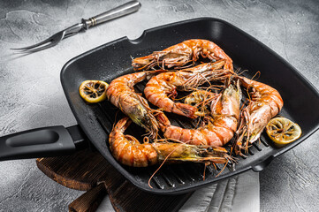 Fried on grill skillet Giant Black tiger prawns shrimps with lemon and herbs. Gray background. Top...