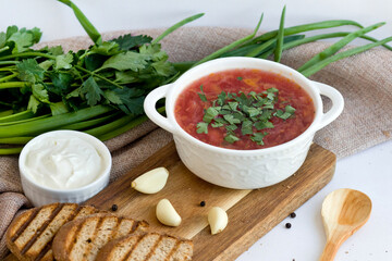 Traditional Russian or Ukrainian borscht with sour cream. Plate on a wooden board with a wooden spoon