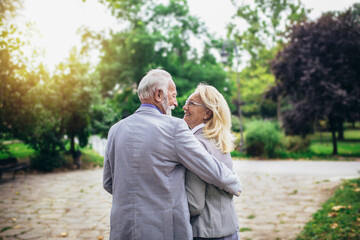 Senior active caucasian couple hugging looks happy in the park in the afternoon