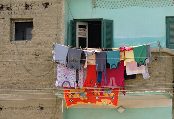 Clothes are hanging to dry outside a window. The wall is typical for Egypt. Part is painted, the other part brickwork with white stones