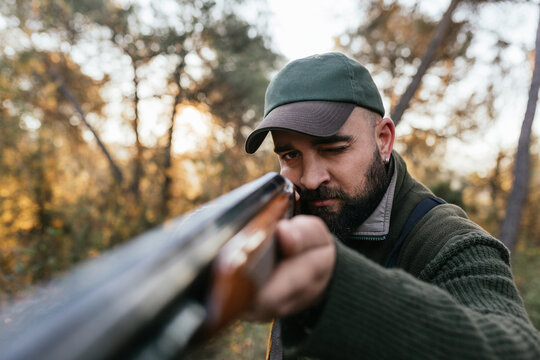 Hunter man aiming his shotgun at camera