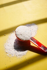 Washing powder in plastic spoon on blue background 