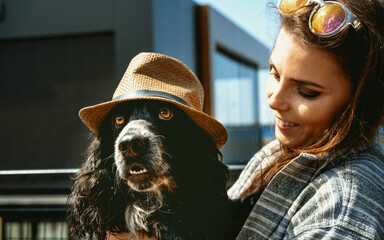 Beautiful spaniel dog in straw hat in arms of owner . Beautiful young girl is holding her pet....