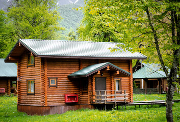 Horizontal photo of  wooden house in  green forest. Pros and cons of  wooden house and suburban real estate concept.