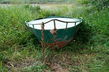 A boat out of the water on the grass, with a chain and padlock