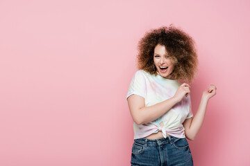 Cheerful young woman looking at camera isolated on pink.