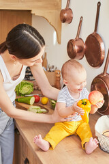 Fototapeta premium A happy smiling boy with his mother in the kitchen cooking together.