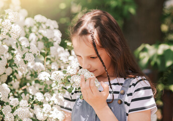 portrait of a smiling little  girl near a flowering tree with white flowers