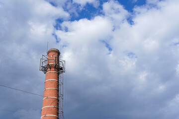 Tall old brick chimney against cloudy sky
