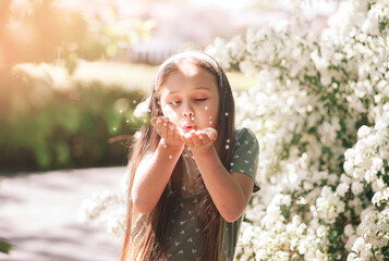 portrait of a smiling little  girl near a flowering tree with white flowers