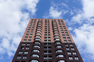 Fototapeta premium Front up view of big modern residential building with apartements with blue sky in background