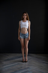 young girl in a t-shirt and shorts on a dark background, full length studio shot