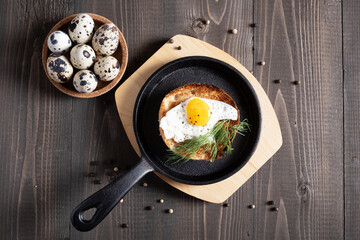 Fried quail egg baked in a round bun in a cast-iron skillet