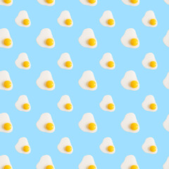 A seamless pattern of broken fresh egg on a blue background