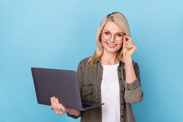 Photo of successful aged lady agent hold netbook enjoy teaching workshop isolated blue color...