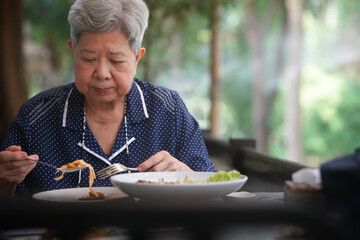 old elderly senior woman eating food on terrace. mature retirement lifestyle