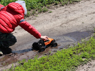 A boy in a red jacket plays with an orange toy monster truck © MIKHAIL BATURITSKII	