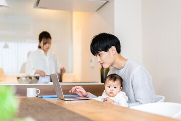 Obraz na płótnie Canvas 赤ちゃんと一緒にパソコンを使うパパ