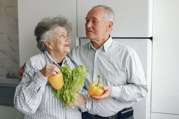 Beautiful old couple prepare food in a kitchen