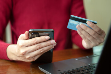 Woman relaxing at home and browsing internet with Laptop, hands holding mobile smart phone and credit card, using banking service, online shopping.