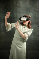Comic portrait of young shocked girl in medieval style dress in vr headset isolated on dark...