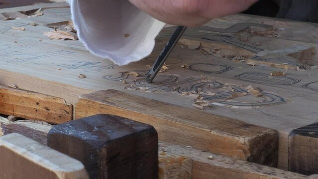 Professional carpenter working in his workshop and carving wood using a gouge, woodworking and craftsmanship concept