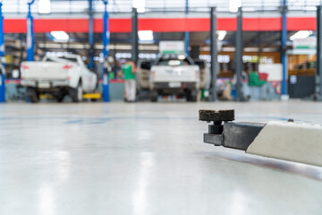 Obraz premium Select focus equipment electric lift for cars in the service put on the epoxy floor in new car factory service , Car repair service center blurred background for industry.