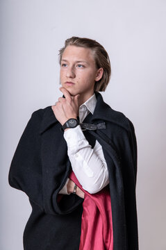 aristokratischer, junger Mann in schwarzem Mantel in Denkerpose