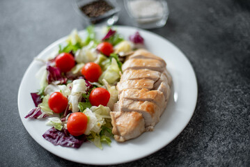 plate with chicken fillet and salad with vegetables on a stone background