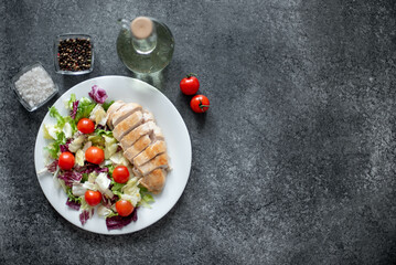 plate with chicken fillet and salad with vegetables on a stone background with copy space for your text