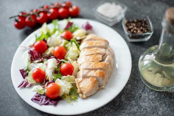 plate with chicken fillet and salad with vegetables on a stone background