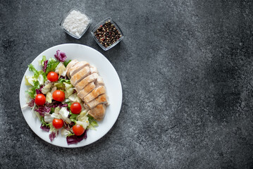 Fototapeta na wymiar plate with chicken fillet and salad with vegetables on a stone background with copy space for your text