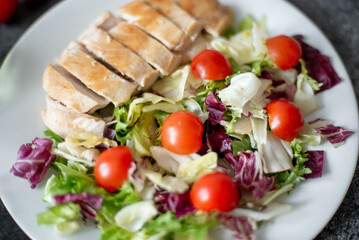 plate with chicken fillet and salad with vegetables on a stone background