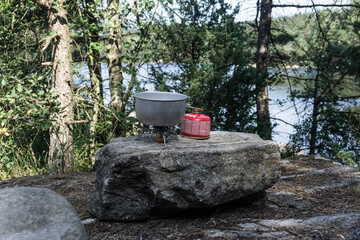 Campingkocher und Metalltopf auf einem Felsen an einem see