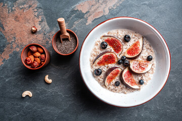 Delicious oatmeal, decorated with fig pieces, strawberries and chia seeds in a bowl, Healthy breakfast Gluten, lactose free, Fitness food. Long banner format, top view