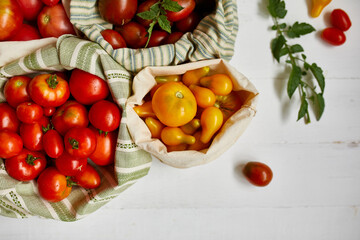 Market delivary of Different kinds of tomatoes in eco textile bag, Zero waste, Eco background, Assortment of tomatoes,  local farmers market, Fresh vegetables, harvest .Top view, copy space.