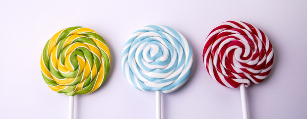 Fototapeta na wymiar Three lollipops on a white background. Horizontal banner