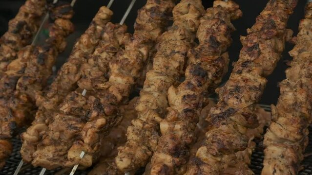 Skewered meat being grilled on a portable open air kitchen grill.