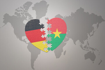 puzzle heart with the national flag of burkina faso and germany on a world map background. Concept.