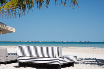 Elegant sofa and umbrella on a tropical beach with palm trees in Isla Mujeres, Mexico