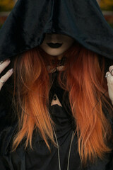 beautiful fashionable young girl witch model stands outdoors in the forest in autumn by the river, pale, vampire, goth