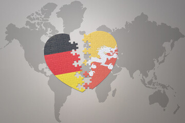 puzzle heart with the national flag of bhutan and germany on a world map background. Concept.