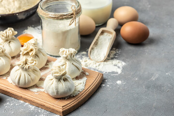 Raw Khinkali with meat on a wooden board. semi-finished products dumplings cooking khinkali on a dark background. Georgian dumplings. place for text, top view