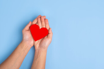 Heart icon. Paper heart in hands on blue background top view space for text.  The concept of Valentine's Day. World heart day