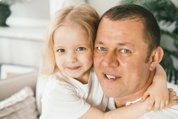 Fototapeta premium A little girl 4 years old gently hugs her dad. 