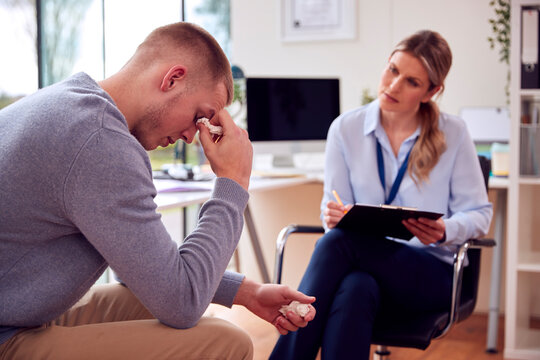 Woman Doctor Or GP In Office Meeting Young Male Patient With Poor Mental Health For Appointment