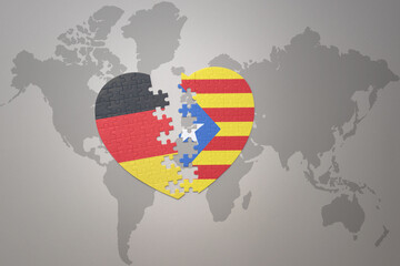 Obraz premium puzzle heart with the national flag of catalonia and germany on a world map background. Concept.