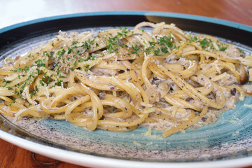 Close up Pasta spaghetti with mushroom cream sauce in porcelain plate on wooden table. Food spaghetti menu concept